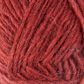 Close-up image of a ball of Léttlopi (Lite Lopi) Icelandic Wool Yarn by Berroco, Inc. in a rich, deep red color. The fibers appear soft and slightly fuzzy, forming intricate patterns as they are wound together, perfect for colorwork knitting.