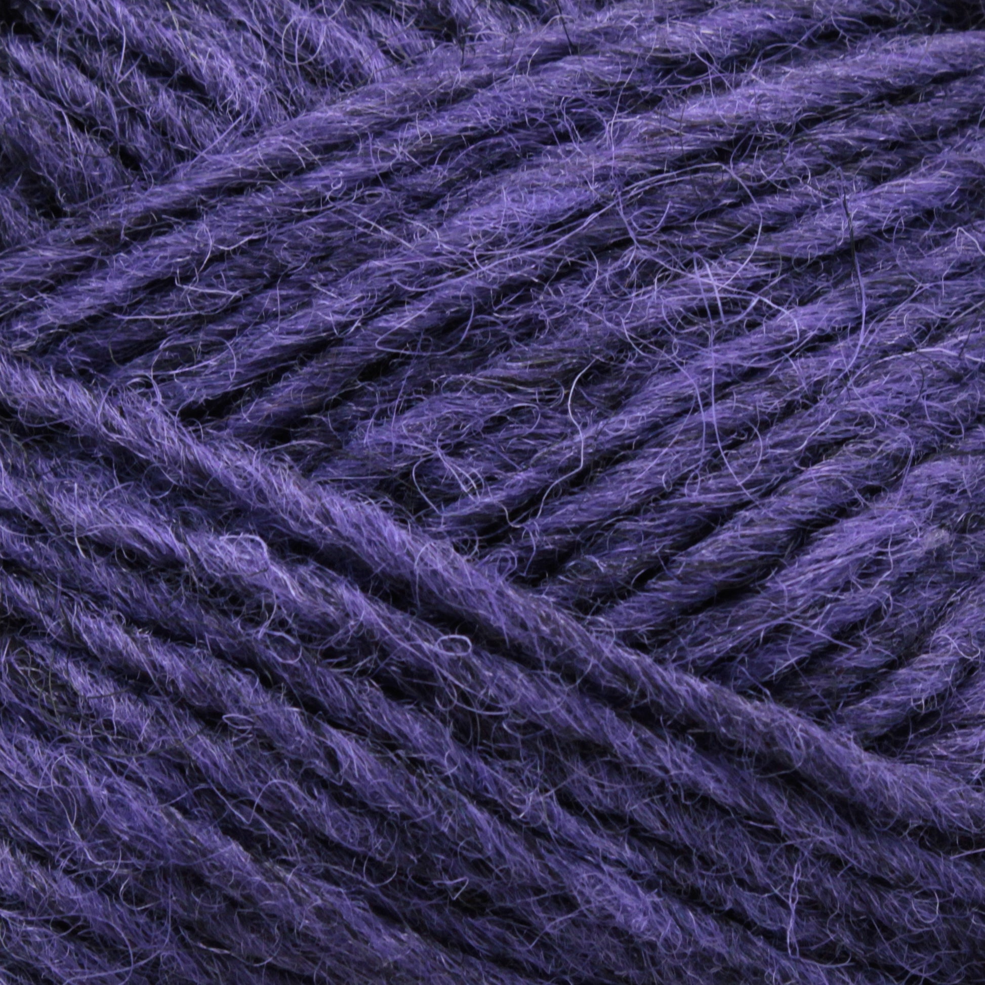 Close-up image of deep purple Léttlopi (Lite Lopi) Icelandic Wool Yarn by Berroco, Inc., showcasing its slightly fuzzy texture and intricately woven individual strands. The yarn appears soft and thick, making it ideal for colorwork knitting or crocheting durable garments.