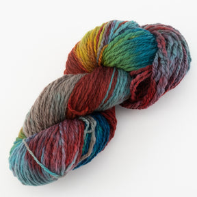 A skein of Great Adirondack Galloway yarn from Great Adirondack Yarn Co, Inc. showcases a thick, multi-colored blend. The hand-dyed yarn boasts a medley of hues such as red, blue, green, yellow, and gray with a slightly twisted texture. Laid out on a plain white background, the vibrant colors and soft, chunky appearance stand out—ideal for crafting cozy accessories.