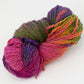 A skein of Great Adirondack Galloway yarn from Great Adirondack Yarn Co, Inc. features a vibrant mix of colors including pink, purple, green, orange, and yellow displayed against a white background. Made from soft merino wool, this thick yarn is perfect for knitting or crocheting accessories.