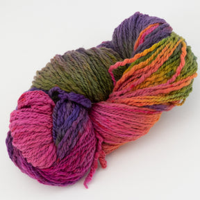 A skein of Great Adirondack Galloway yarn from Great Adirondack Yarn Co, Inc. features a vibrant mix of colors including pink, purple, green, orange, and yellow displayed against a white background. Made from soft merino wool, this thick yarn is perfect for knitting or crocheting accessories.