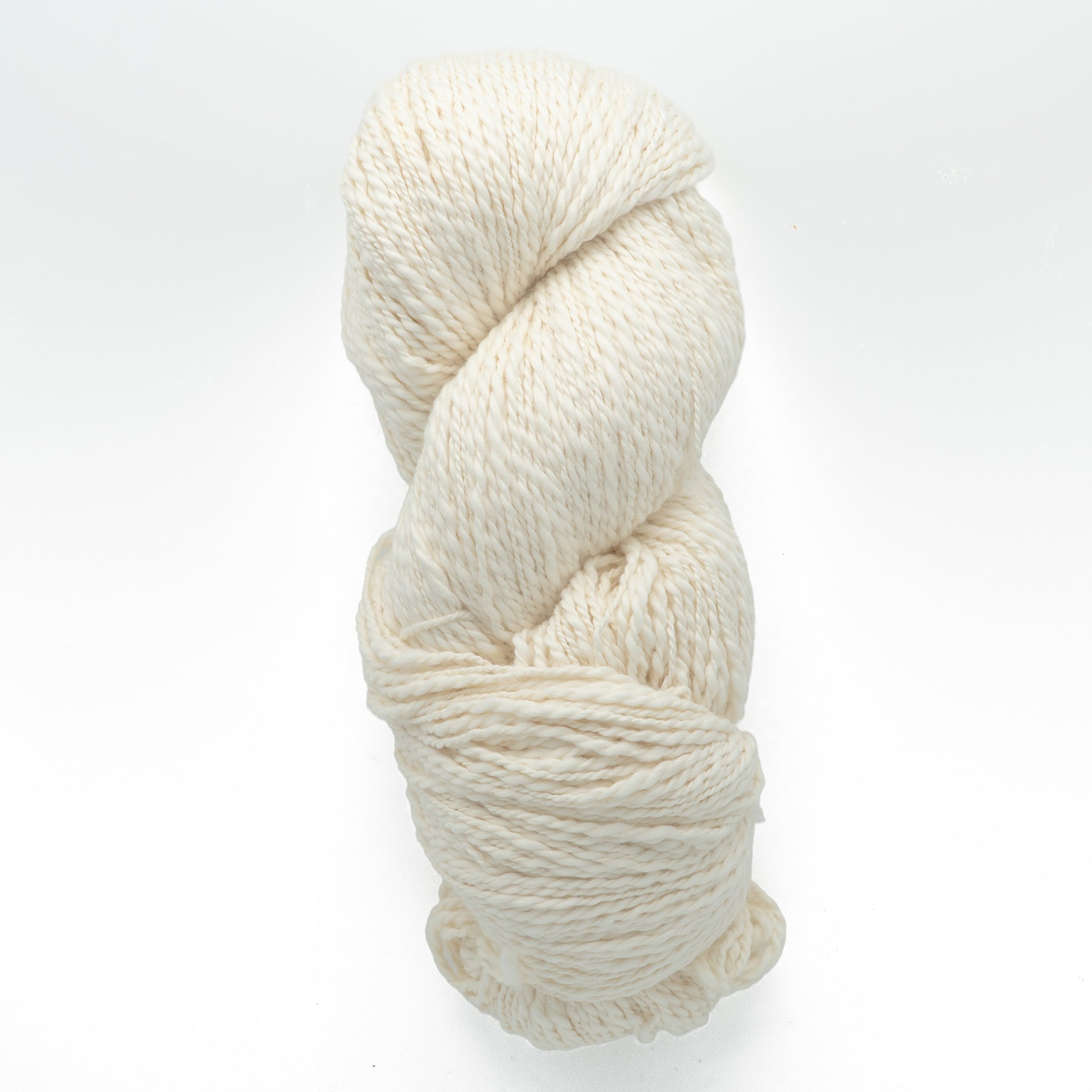 A neatly coiled skein of Henry's Attic's Inca Organic Cotton, featuring off-white, textured yarn against a plain white background. The yarn appears thick and soft, making it ideal for knitting or crocheting projects.