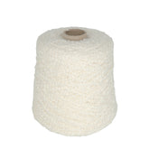 A large spool of Tess Cotton Yarn by Henry's Attic, featuring an off-white boucle texture with its unique looped surface, is wound around a cylindrical cardboard core and positioned upright against a plain white background.