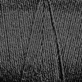 Close-up image of dark gray Cotton Carpet Warp 8/4 yarn by Great Northern Weaving, tightly wound into a ball and displaying a detailed texture of the fine fibers and strands. Often used for rag rugs, the yarn is arranged in a crisscross pattern, showcasing its soft and slightly fuzzy surface.