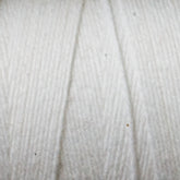 Close-up image of Great Northern Weaving's Cotton Carpet Warp 8/4. The texture is soft and slightly fluffy, with a subtle diagonal pattern indicating the way the yarn is twisted. Small fibers are visible, enhancing the detailed appearance and reminiscent of those found in handmade coverlets.