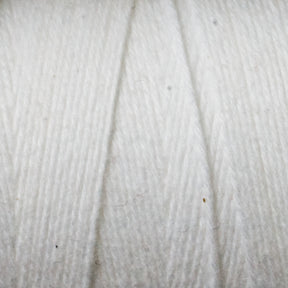 Close-up image of Great Northern Weaving's Cotton Carpet Warp 8/4. The texture is soft and slightly fluffy, with a subtle diagonal pattern indicating the way the yarn is twisted. Small fibers are visible, enhancing the detailed appearance and reminiscent of those found in handmade coverlets.