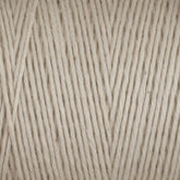 Close-up image of Great Northern Weaving’s Cotton Carpet Warp 8/4 in beige. The detailed texture reveals tightly spun fibers with a slightly uneven, natural look. The color is a soft, neutral beige with subtle tonal variations, providing a warm and cozy feel ideal for knitting or crocheting projects such as cozy coverlets.