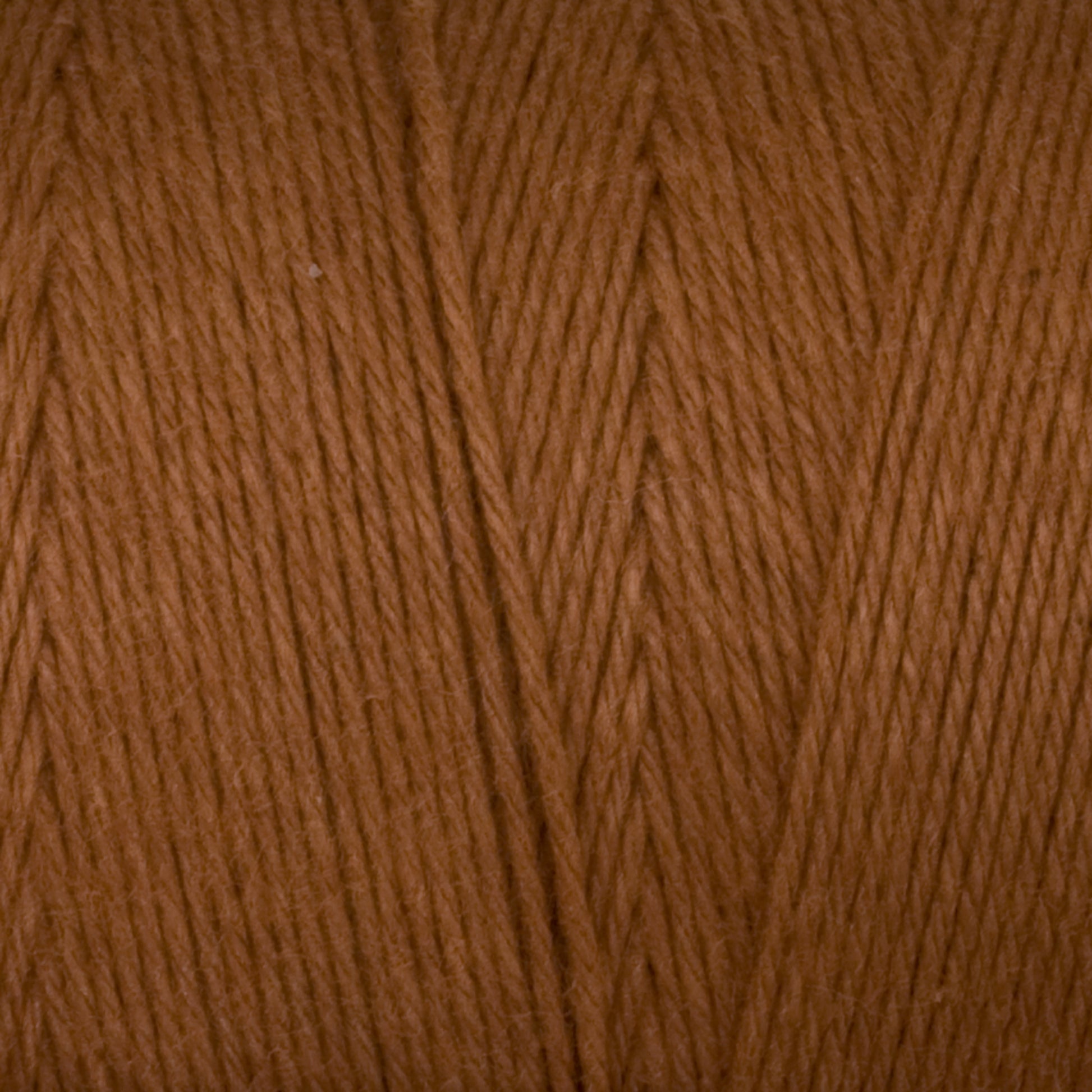 Close-up image of the warm, brown **Cotton Carpet Warp 8/4** by **Great Northern Weaving**. The texture shows detailed strands of twisted fibers, highlighting the soft and smooth appearance typical of this high-quality cotton warp yarn. The consistent color gives an impression of an evenly dyed material ideal for creating exquisite rag rugs.