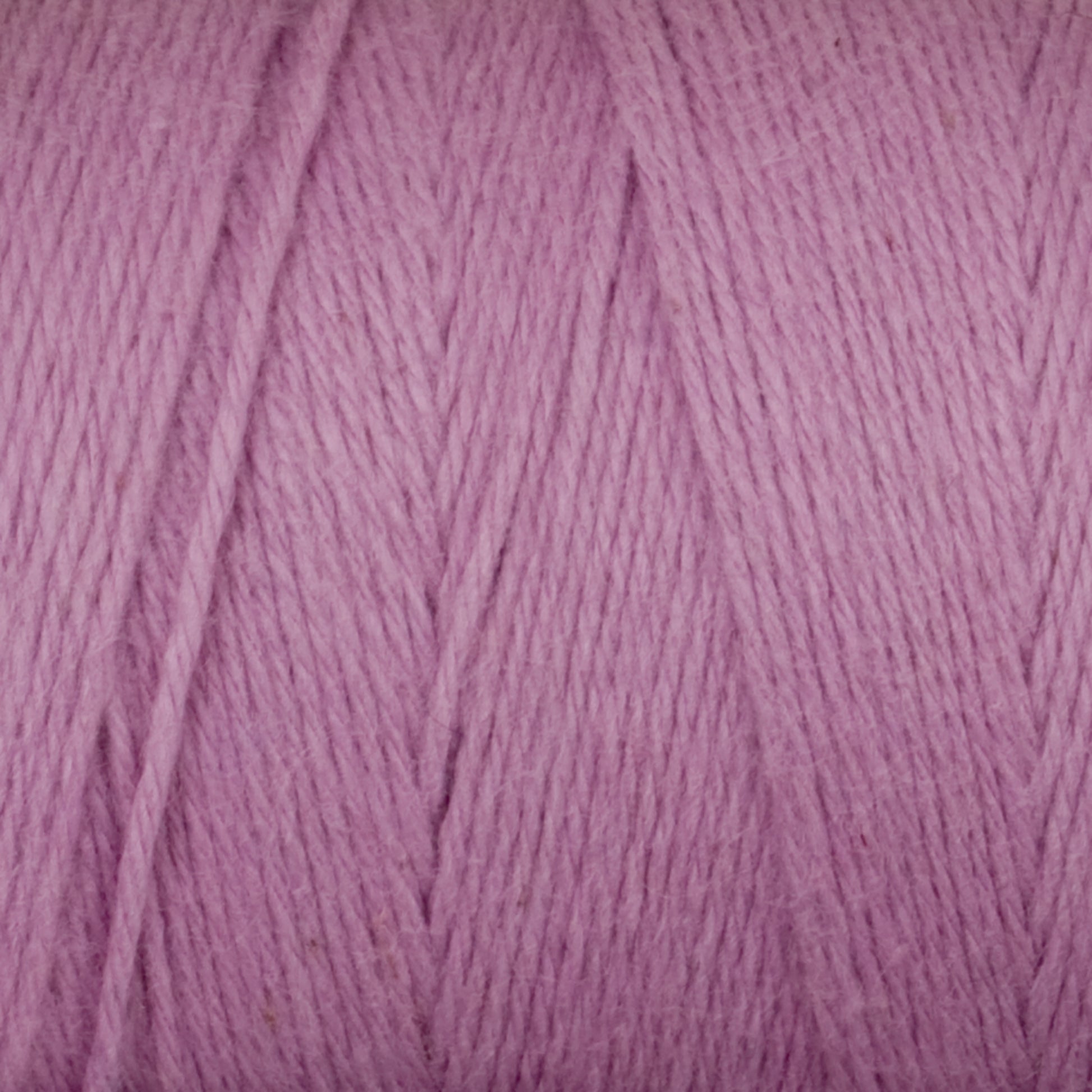 Close-up of a ball of Cotton Carpet Warp 8/4 from Great Northern Weaving in a soft pastel purple color. The cotton warp yarn fibers appear thick and smooth, with visible texture and strands neatly wound together. The color is consistent throughout, creating a gentle and cozy feel, reminiscent of handmade coverlets.