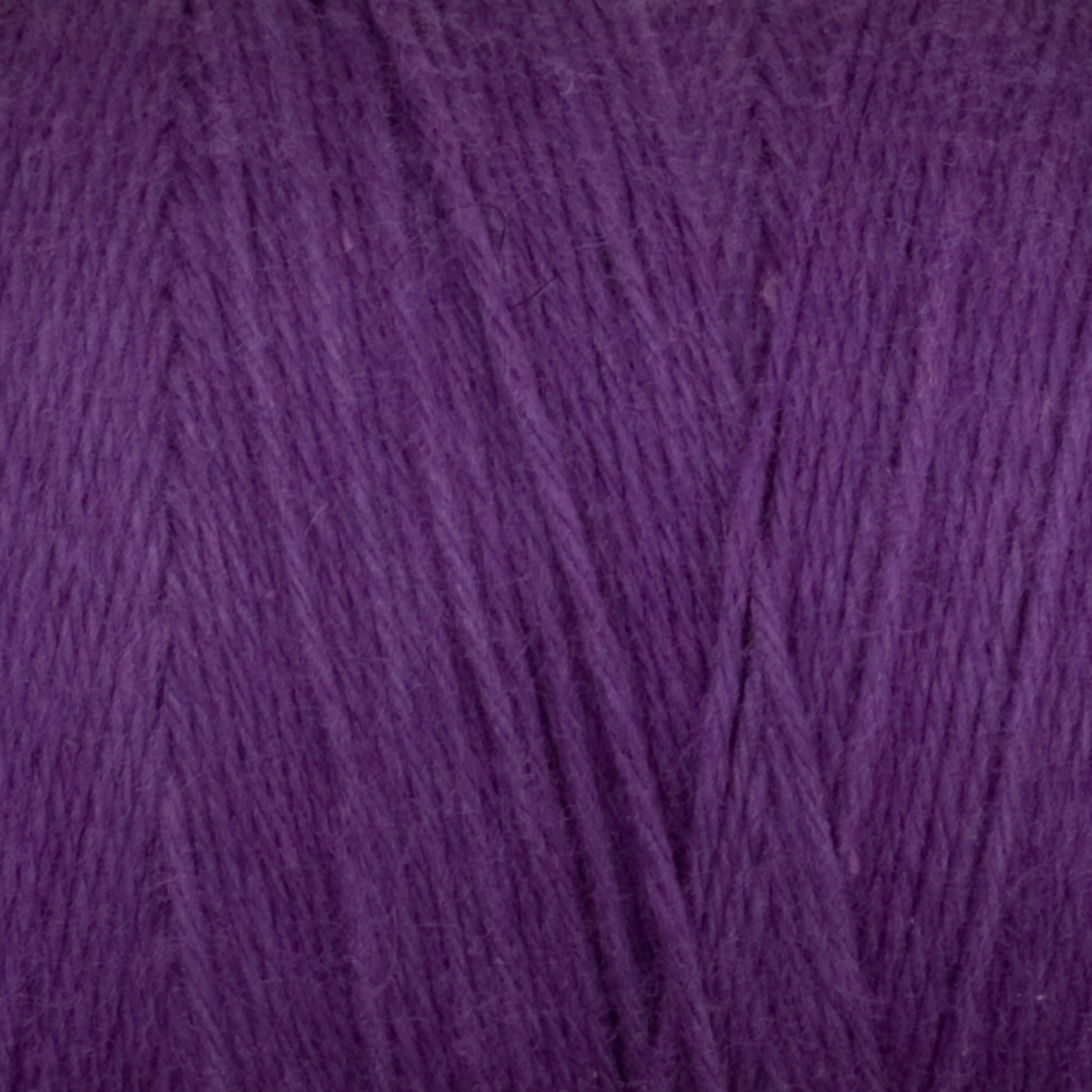 Close-up of Great Northern Weaving's Cotton Carpet Warp 8/4, showcasing the texture and fine fibers woven together to form a dense, soft material. The warp yarn displays a rich, deep purple color with subtle variations in shade, highlighting the natural twists and patterns formed in the thread.