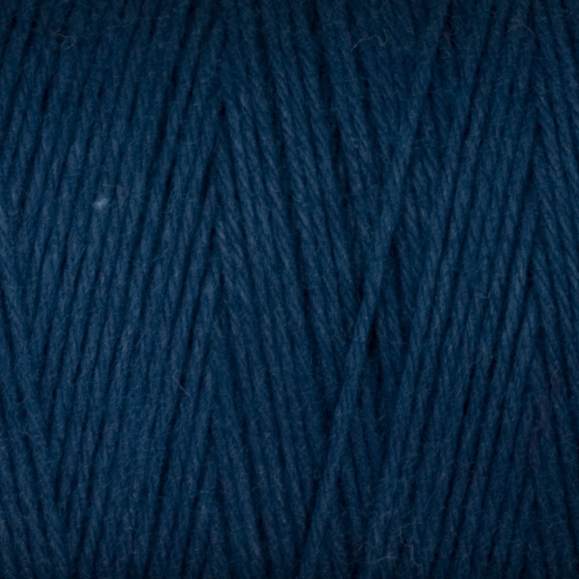 A close-up of Great Northern Weaving's Cotton Carpet Warp 8/4 in dark blue. The yarn strands are neatly wound, creating a textured pattern across the image. The color is deep and rich, with a slight sheen highlighting the individual fibers—perfect for crafting rag rugs or coverlets.