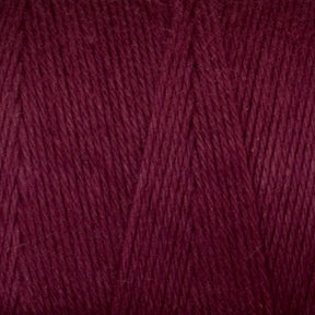 A close-up view of Great Northern Weaving's Cotton Carpet Warp 8/4 yarn, often used in rag rugs. The texture is soft and slightly fuzzy, with individual strands twisted together, creating a uniform and tightly knit pattern. The rich, deep maroon color is consistent throughout the yarn.