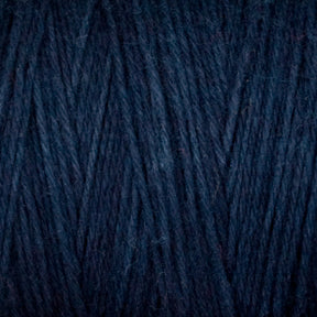 Close-up image of Great Northern Weaving's Cotton Carpet Warp 8/4 in dark blue, showcasing its tightly woven texture. The intertwined yarn fibers create a consistent pattern and dense appearance, reminiscent of materials used in traditional rag rugs.