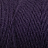 Close-up shot of Great Northern Weaving's Cotton Carpet Warp 8/4 in dark purple, showcasing its texture and tightly-wound strands. The fibers appear soft and smooth, suitable for knitting, crochet projects, or crafting coverlets.