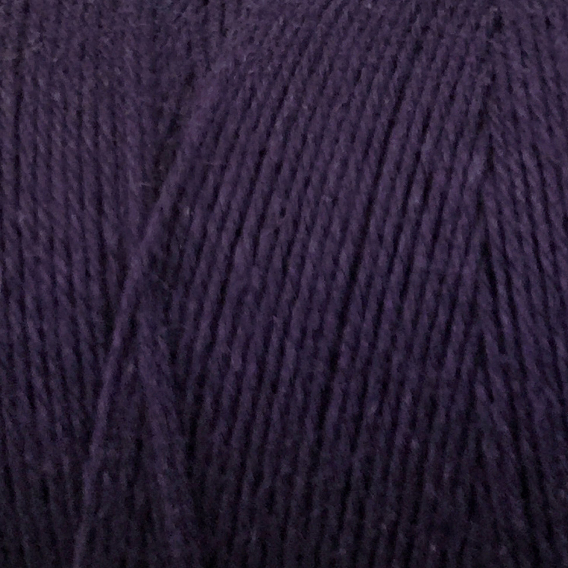 Close-up shot of Great Northern Weaving's Cotton Carpet Warp 8/4 in dark purple, showcasing its texture and tightly-wound strands. The fibers appear soft and smooth, suitable for knitting, crochet projects, or crafting coverlets.