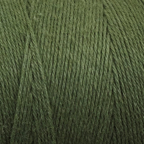 A close-up view of a thick spool of Great Northern Weaving's Cotton Carpet Warp 8/4 in green. The tightly wound fibers show a slightly fuzzy texture, perfect for crafting rag rugs or coverlets. The yarn appears to be of medium weight and has a natural, muted green color.