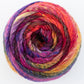 A close-up image of the Noro Ito yarn ball by Knitting Fever / Euro Yarns. The variegated yarn is arranged in a spiral pattern, showcasing a blend of vibrant colors including red, purple, pink, orange, blue, and yellow. The texture appears soft and slightly fluffy.