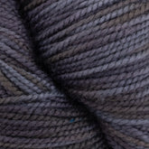 Close-up image of a skein of dark gray Happy Feet Sock Yarn by Plymouth Yarn Co. The yarn appears tightly wound and textured, featuring varying shades of gray with hints of interwoven blue threads. The surface showcases a mix of light and shadow, emphasizing the fibrous texture of this durable knitting yarn made from superwash Merino wool.