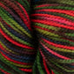 Close-up of durable Happy Feet Sock Yarn from Plymouth Yarn Co. featuring bright and vibrant shades of red, green, purple, and brown. Made from merino wool, the yarn is tightly wound, showcasing the various colors in twisted, parallel strands for a lively and textured appearance.