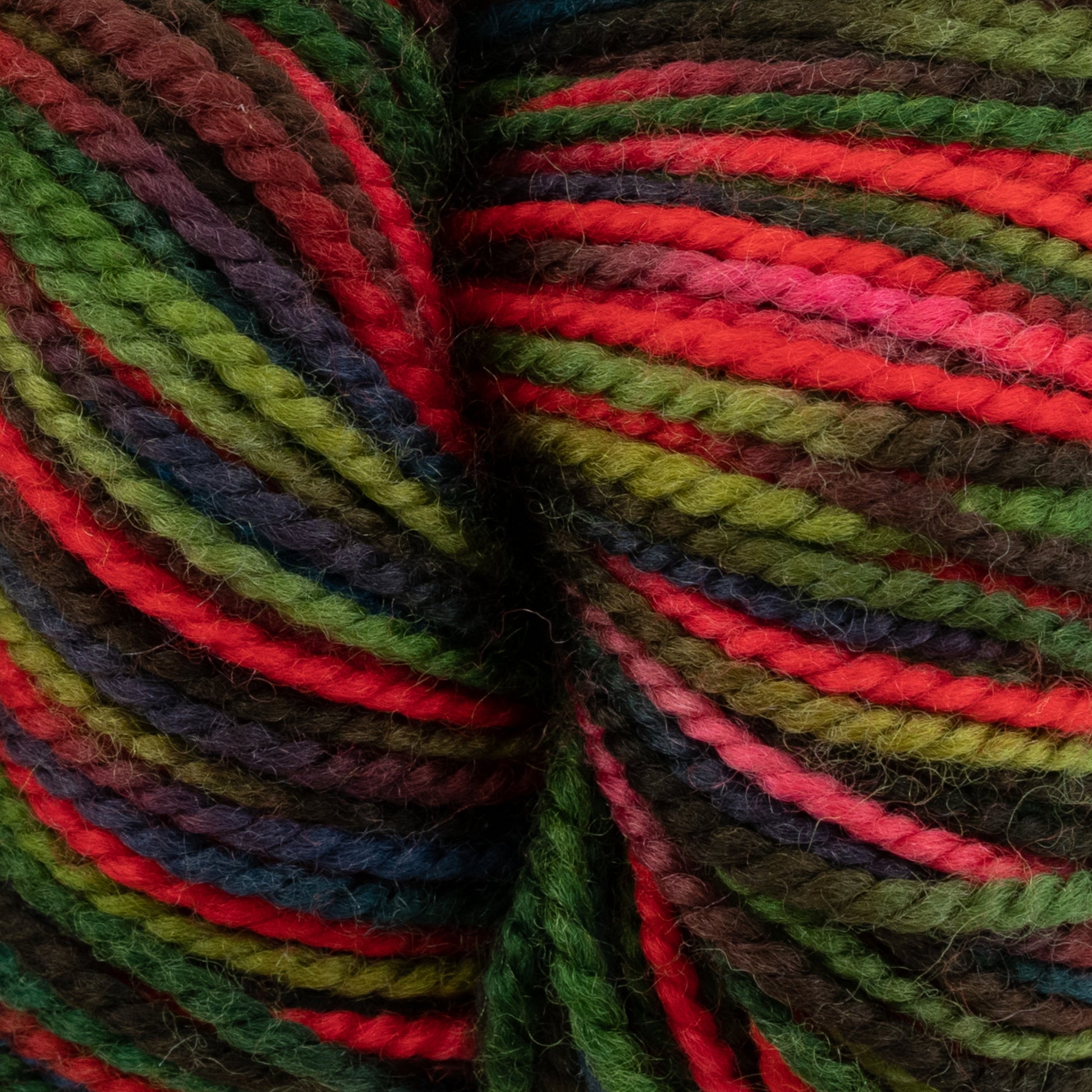 Close-up of durable Happy Feet Sock Yarn from Plymouth Yarn Co. featuring bright and vibrant shades of red, green, purple, and brown. Made from merino wool, the yarn is tightly wound, showcasing the various colors in twisted, parallel strands for a lively and textured appearance.