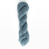 A neatly twisted skein of Jade Sapphire Cashmere 2-Ply yarn from Jade Sapphire Exotic Fibres, showcasing its soft, blue-grey hues against a plain white background. The hand-dyed colors appear smooth and tightly wound, ready for use in knitting or crochet projects such as lacy scarves and woven accessories.