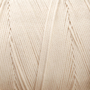 Close-up view of a tightly wound, cream-colored spool of Glimakra's Swedish Cotton Warp (Seine Twine, Fiskgarn). The texture of the fibers is visible, showcasing the intricate pattern of the cotton warp yarns' strands. The yarn appears smooth and evenly wound around the spool.