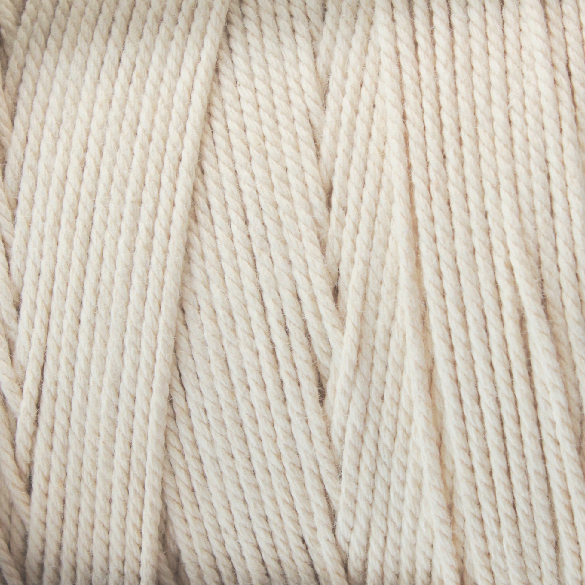 A close-up view of Glimakra's Swedish Cotton Warp (Seine Twine, Fiskgarn) in beige, showing tightly coiled strands. The texture appears soft and slightly fuzzy, with light shadows enhancing the twists and loops of the individual threads.