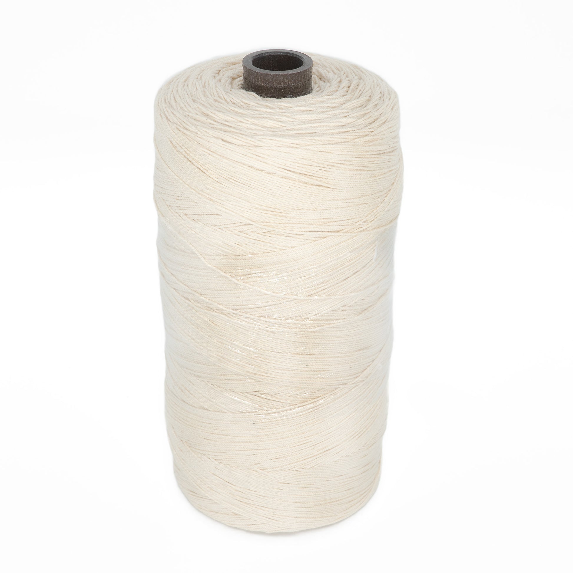 A close-up of a large spool of Glimakra's Swedish Cotton Warp (Seine Twine, Fiskgarn). The cylindrical spool is tightly wrapped with off-white cotton thread and features a dark brown core. The background is plain white, making the spool the focal point of the image.