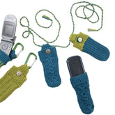 A delightful assortment of Halcyon Yarn's Cell Bags, available for download, features charming crocheted designs in blue and green hues. Each holder showcases unique closures such as buttons and braided cords. The bags are pictured with two flip phones partially inserted, some adorned with green carabiners. These coordinated cell bags are a wonderful social tool for staying connected.