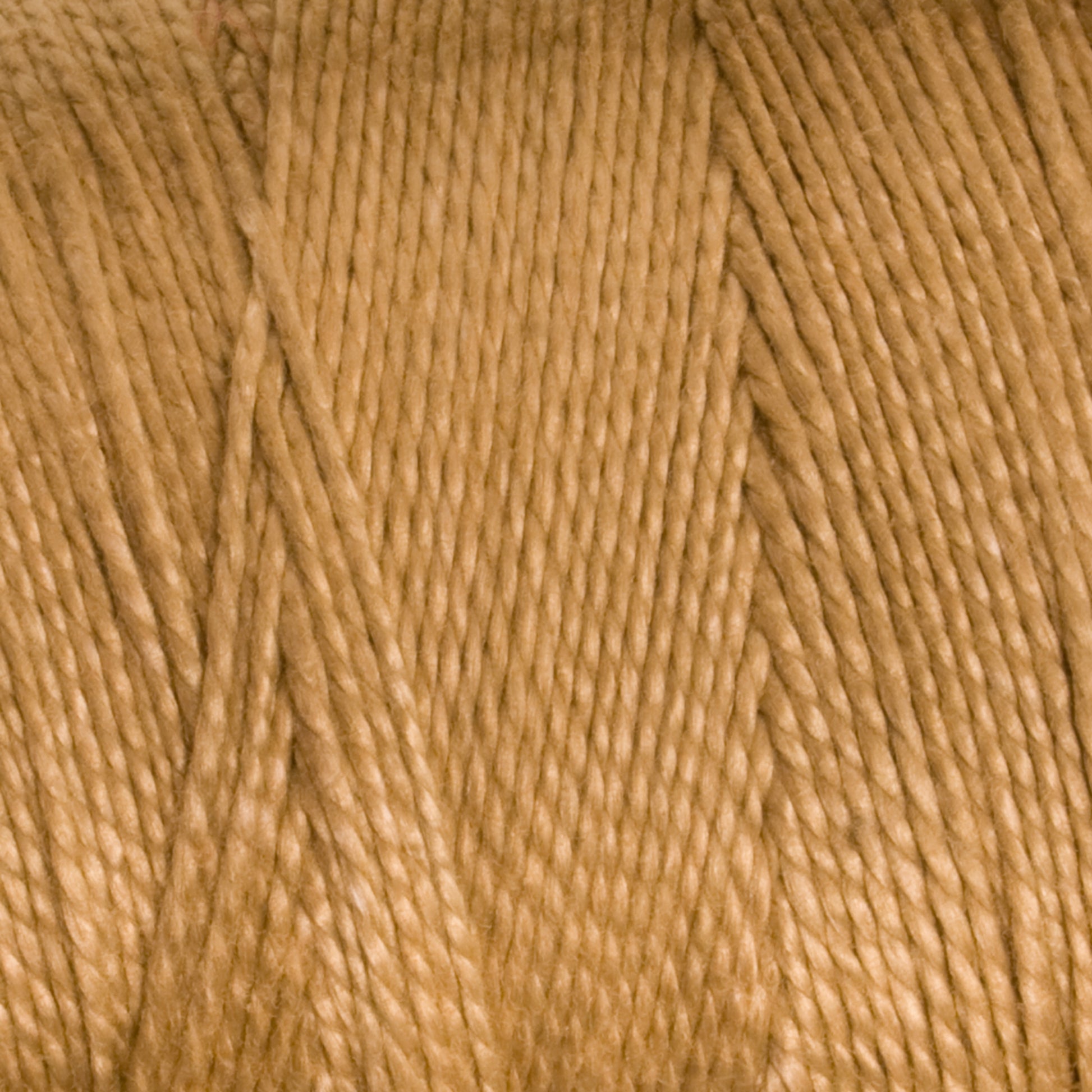 A close-up shot of tan-colored 3/2 Pearl Cotton Yarn from Supreme Corp, showcasing the mercerized cotton's texture and intertwined strands. The versatile yarn appears smooth and tightly wound.