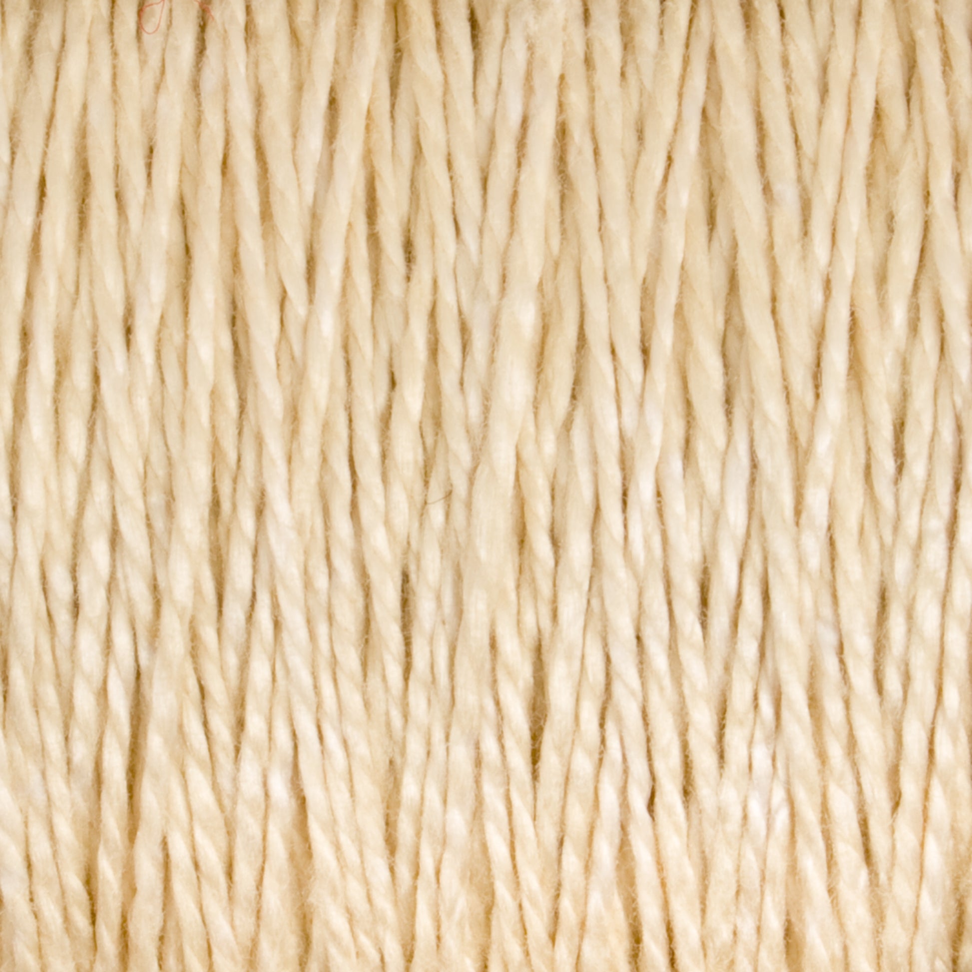 Close-up view of the tightly wound strands of 3/2 Pearl Cotton Yarn from Supreme Corp, showcasing their texture and twisted pattern. The natural, beige fibers appear slightly rough and are packed closely together, creating a uniform, organic appearance reminiscent of versatile yarn.