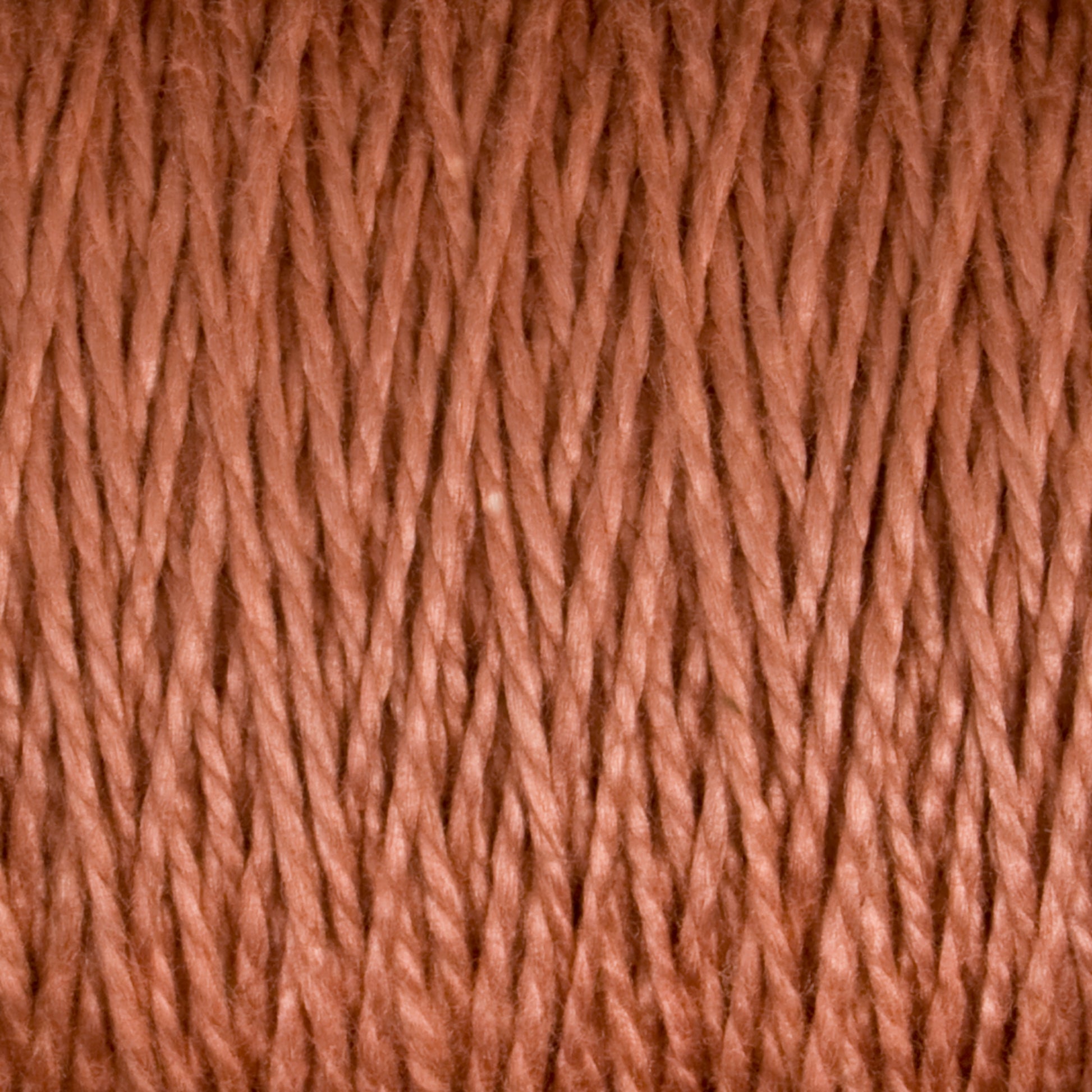 Close-up of the 3/2 Pearl Cotton Yarn | Mini-cone from Supreme Corp, showcasing a detailed texture of tightly wound, interwoven fibers. The yarn appears soft and consistent, with subtle variations in hue and thickness. The image captures the intricate and repetitive pattern of the versatile yarn strands.