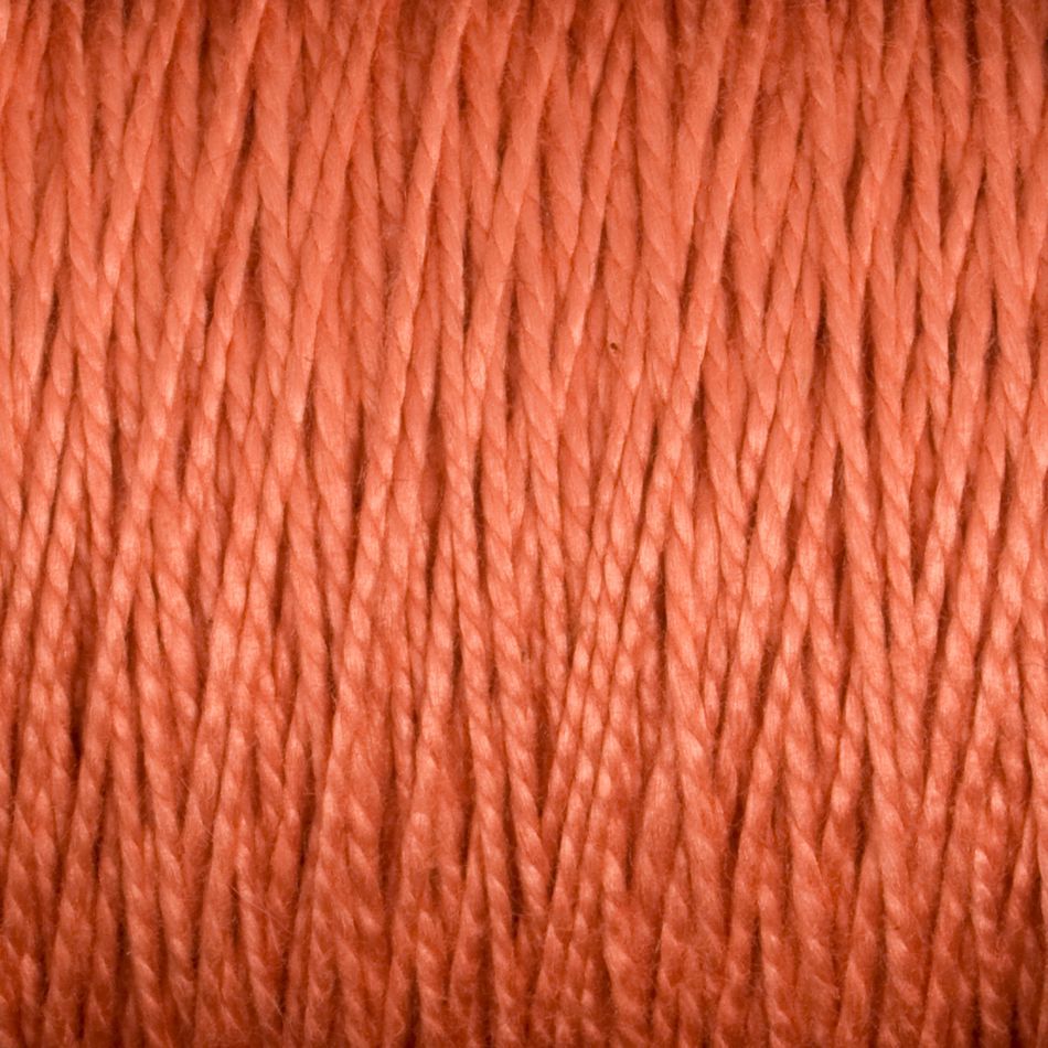 Close-up image of a spool of thick, orange-brown 3/2 Pearl Cotton Yarn. The yarn is tightly wound, showcasing its individual strands and textured surface. The lighting emphasizes the fibrous and slightly reflective quality, reminiscent of versatile yarn by Supreme Corp.