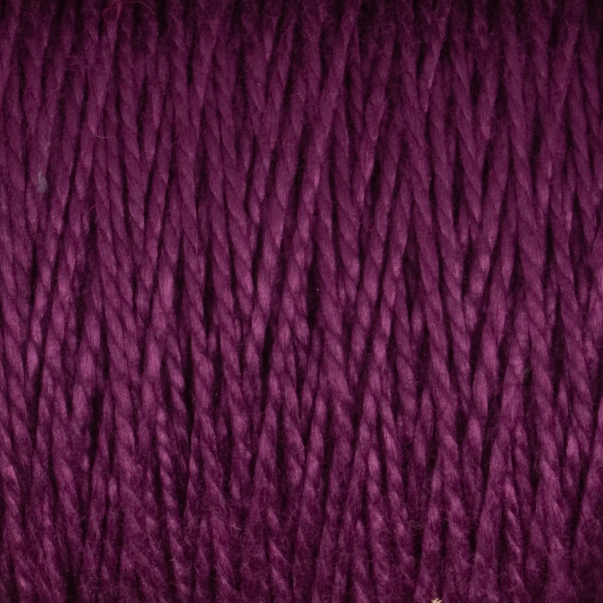 Experience a close-up view of the 3/2 Pearl Cotton Yarn | Mini-cone by Supreme Corp, showcasing its twisted strands of deep purple, mercerized cotton yarn. The texture is clearly visible, revealing tightly wound fibers with a slight sheen. The rich, vibrant color accentuates the pattern and intricacy of each individual strand.