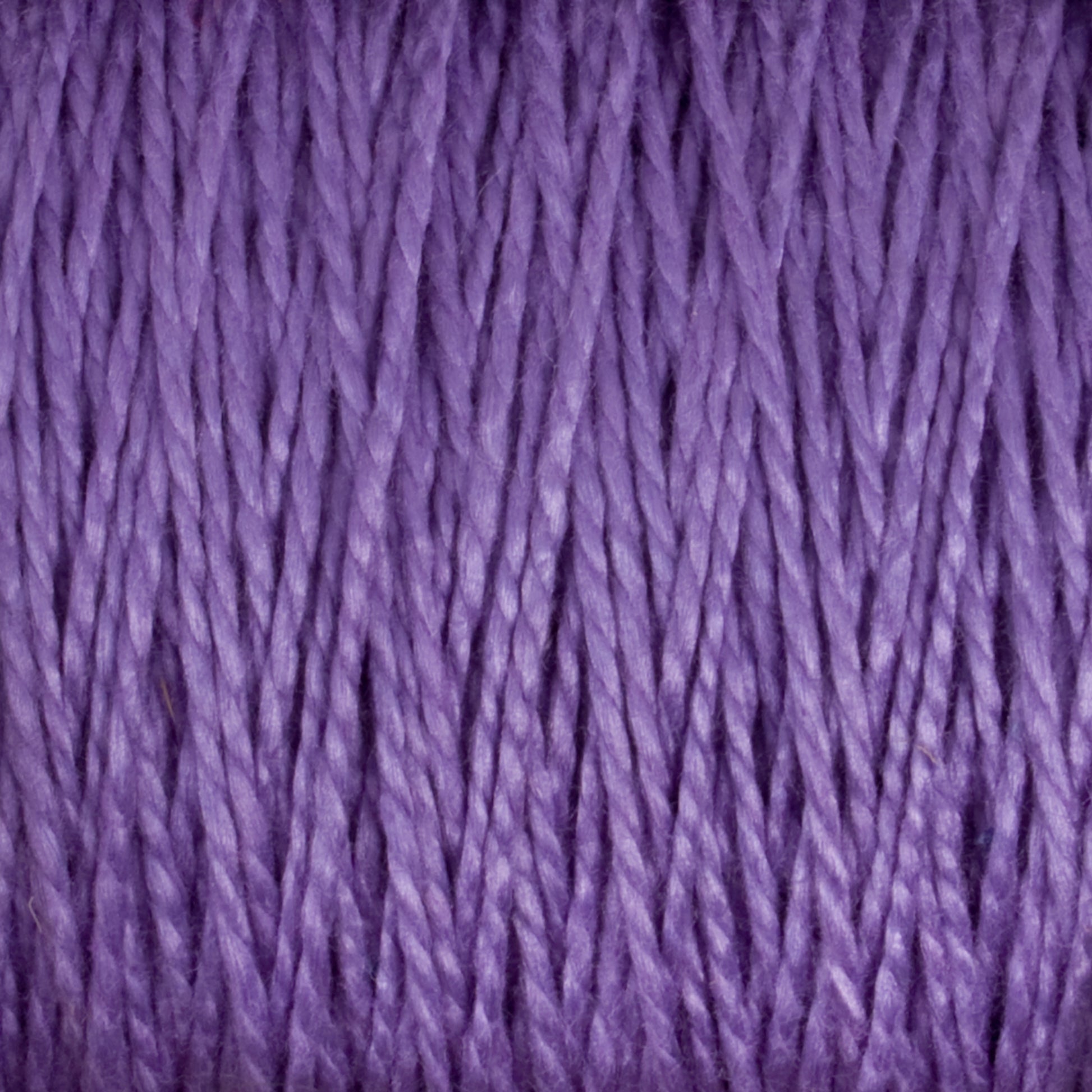 Close-up view of tightly wound, textured strands of Supreme Corp's 3/2 Pearl Cotton Yarn in purple, creating a visually rich pattern. The fibers appear slightly reflective, enhancing the depth and variation in the purple tones.