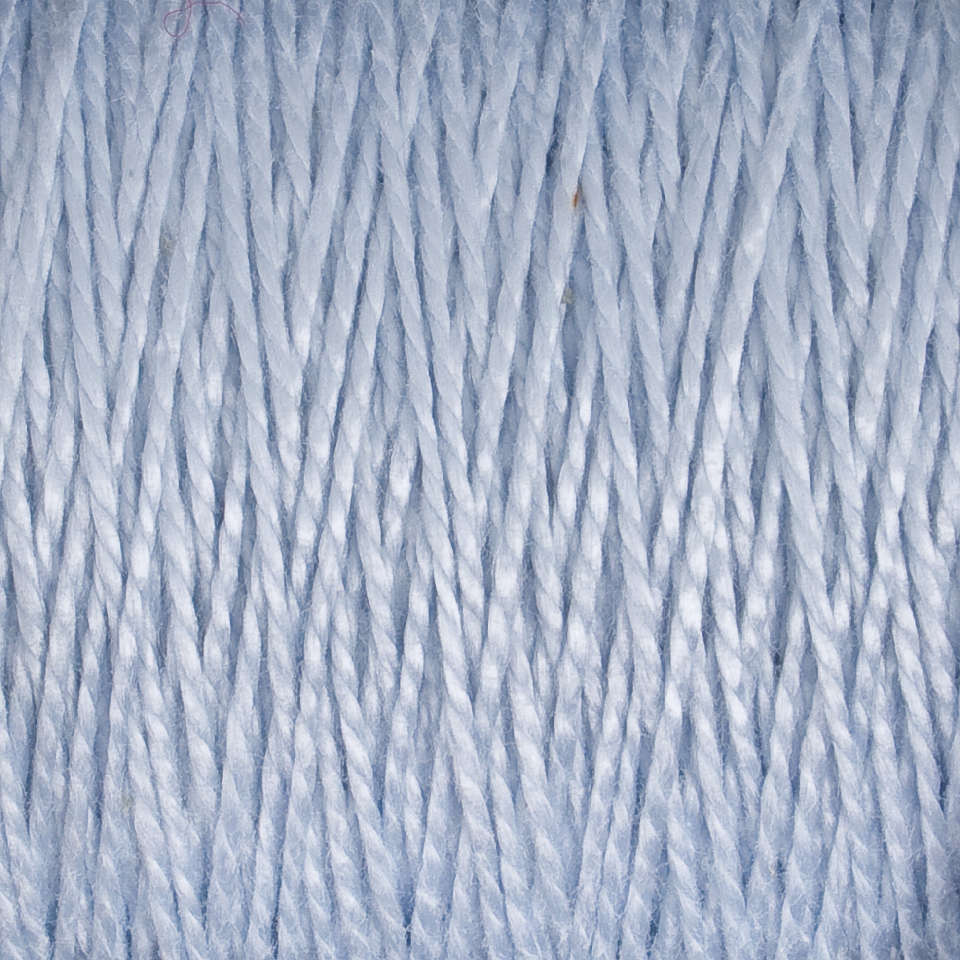 Close-up of tightly wound light blue 3/2 Pearl Cotton Yarn | Mini-cone by Supreme Corp. The individual fibers are visible, showing a textured and slightly shiny appearance. The image captures the repetitive, parallel strands, highlighting the intricate detail of this versatile material.