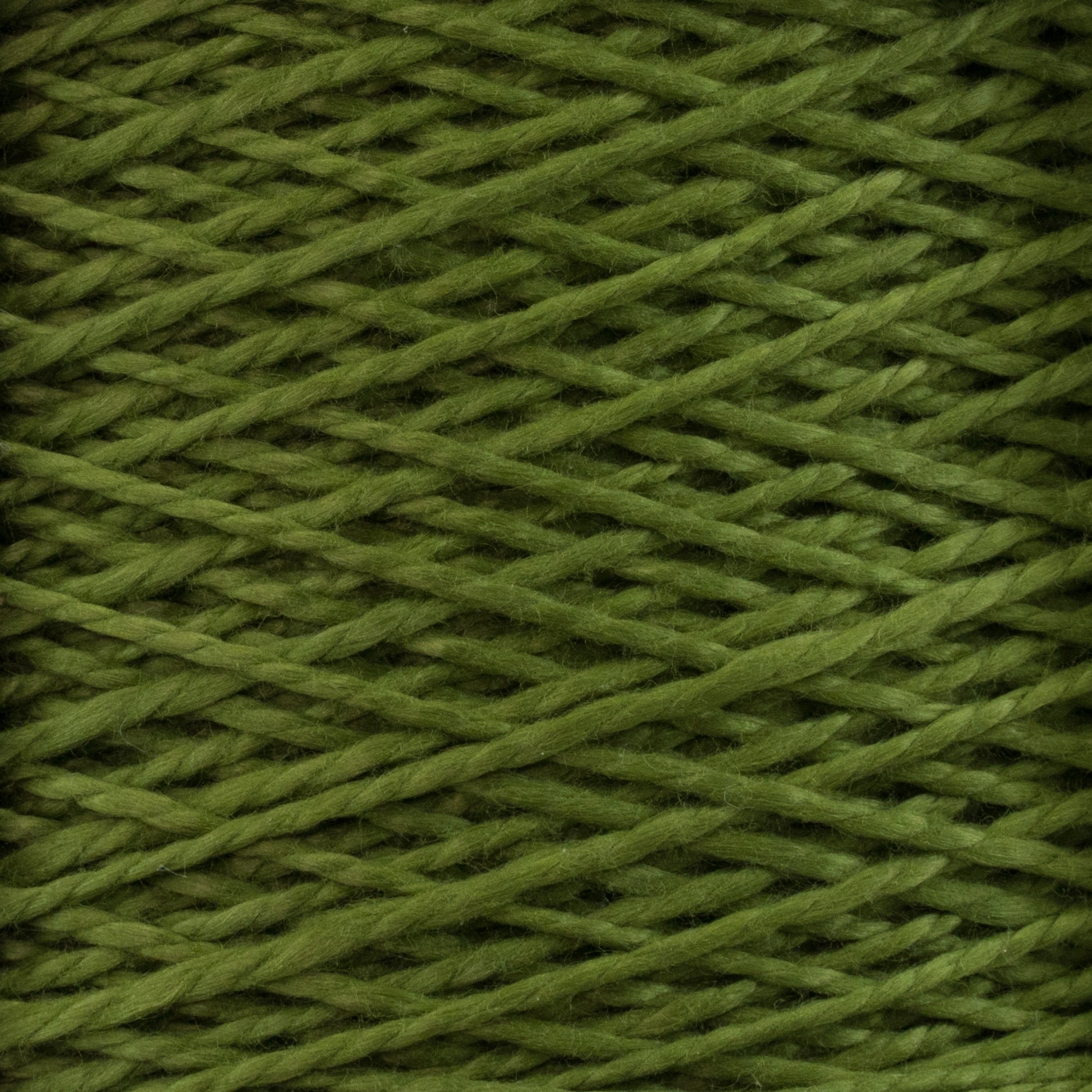 Close-up image of Supreme Corp's 3/2 Pearl Cotton Yarn in green, showcased on a mini-cone. The tightly wound strands feature a criss-cross pattern, and the yarn's texture looks soft and slightly fuzzy with a uniform and consistent color throughout.