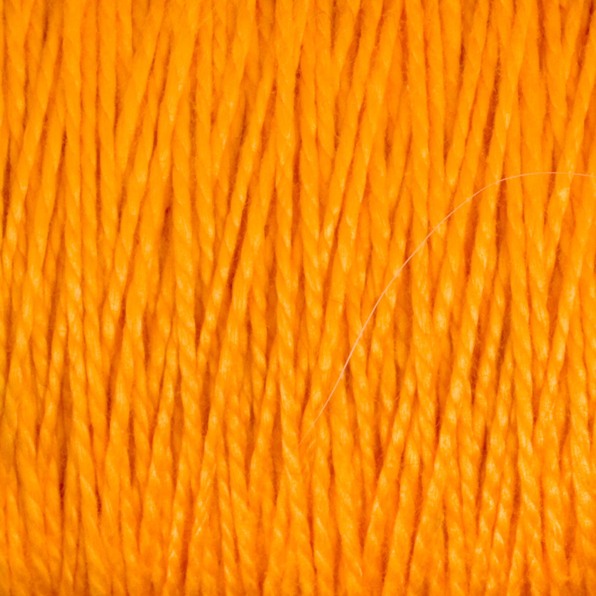 A close-up image of the 3/2 Pearl Cotton Yarn from Supreme Corp reveals strands of mercerized cotton yarn tightly wound together, creating a textured surface with visible twists and fibers. The vibrant orange color stands out, giving a warm and lively appearance.