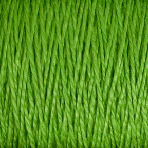 Close-up of 3/2 Pearl Cotton Yarn from Supreme Corp, tightly woven and showcasing its texture. The smooth and uniform strands feature a vibrant, bright green color. This versatile yarn, made from mercerized cotton, highlights the detailed fiber structure and thickness, making it perfect for various crafting projects. Available in a large cone for all your creative needs.