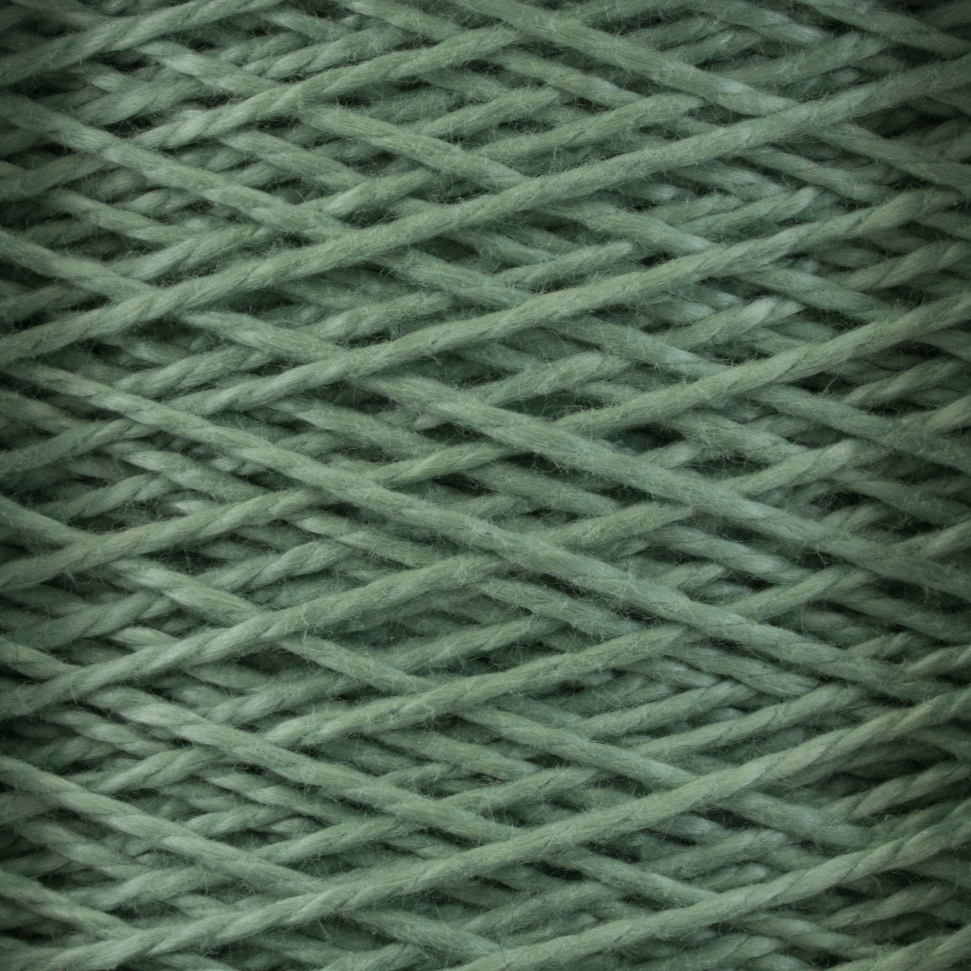 Close-up image of Supreme Corp’s 3/2 Pearl Cotton Yarn | Mini-cone in a vibrant green hue, wound tightly in a crisscross pattern to create a textured and interwoven appearance. The yarn is neatly wrapped, showcasing the soft and fibrous material.