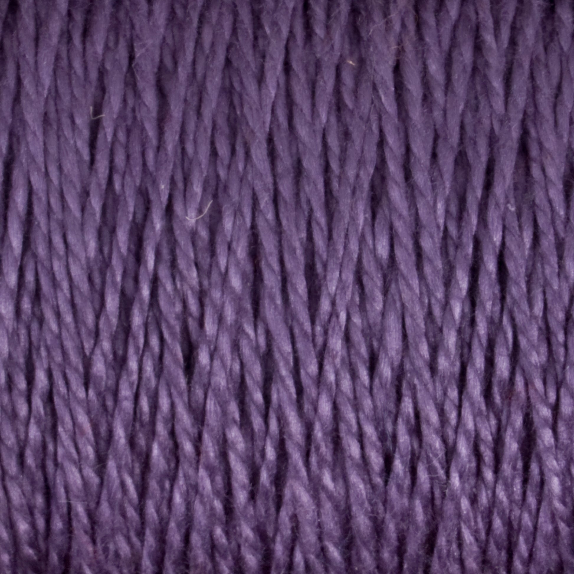 Close-up image of Supreme Corp's 3/2 Pearl Cotton Yarn | Mini-cone in a rich purple hue. The texture reveals tightly twisted strands, suggesting a smooth, slightly shiny finish that is perfect for knitting or crocheting projects. This versatile yarn is ideal for various craft endeavors.