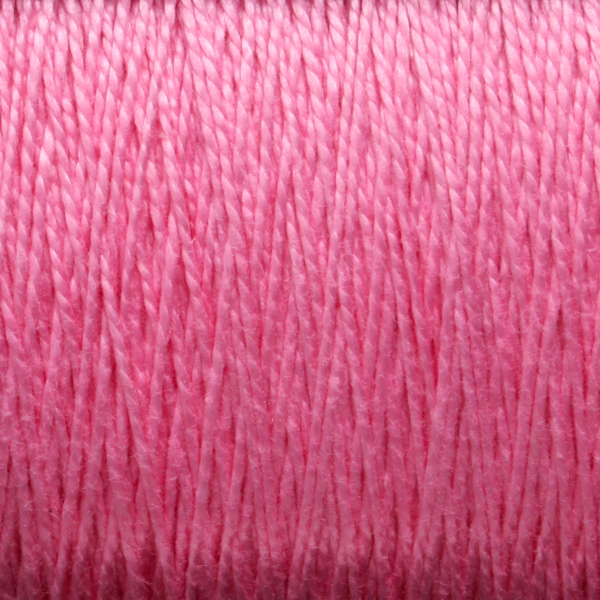 Close-up of tightly wound 3/2 Pearl Cotton Yarn | Mini-cone from Supreme Corp, revealing the texture and individual strands. The yarn appears smooth and glossy, with a slightly reflective surface, and the vibrant pink color remains consistent throughout.