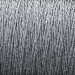 Close-up image of a mini-cone of Supreme Corp's 3/2 Pearl Cotton Yarn in gray, tightly wound in parallel layers, creating a textured pattern with visible strands. The image highlights the details of the mercerized cotton yarn's fibers and the uniformity of the winding.