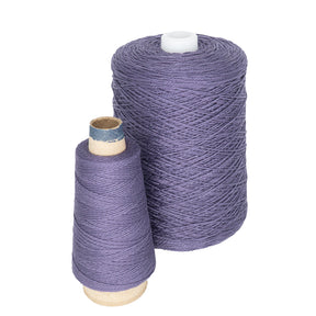 A large spool of purple 3/2 Pearl Cotton Yarn by Supreme Corp on a cone is paired with a smaller cylindrical spool, both crafted from mercerized cotton yarn, set against a white background.