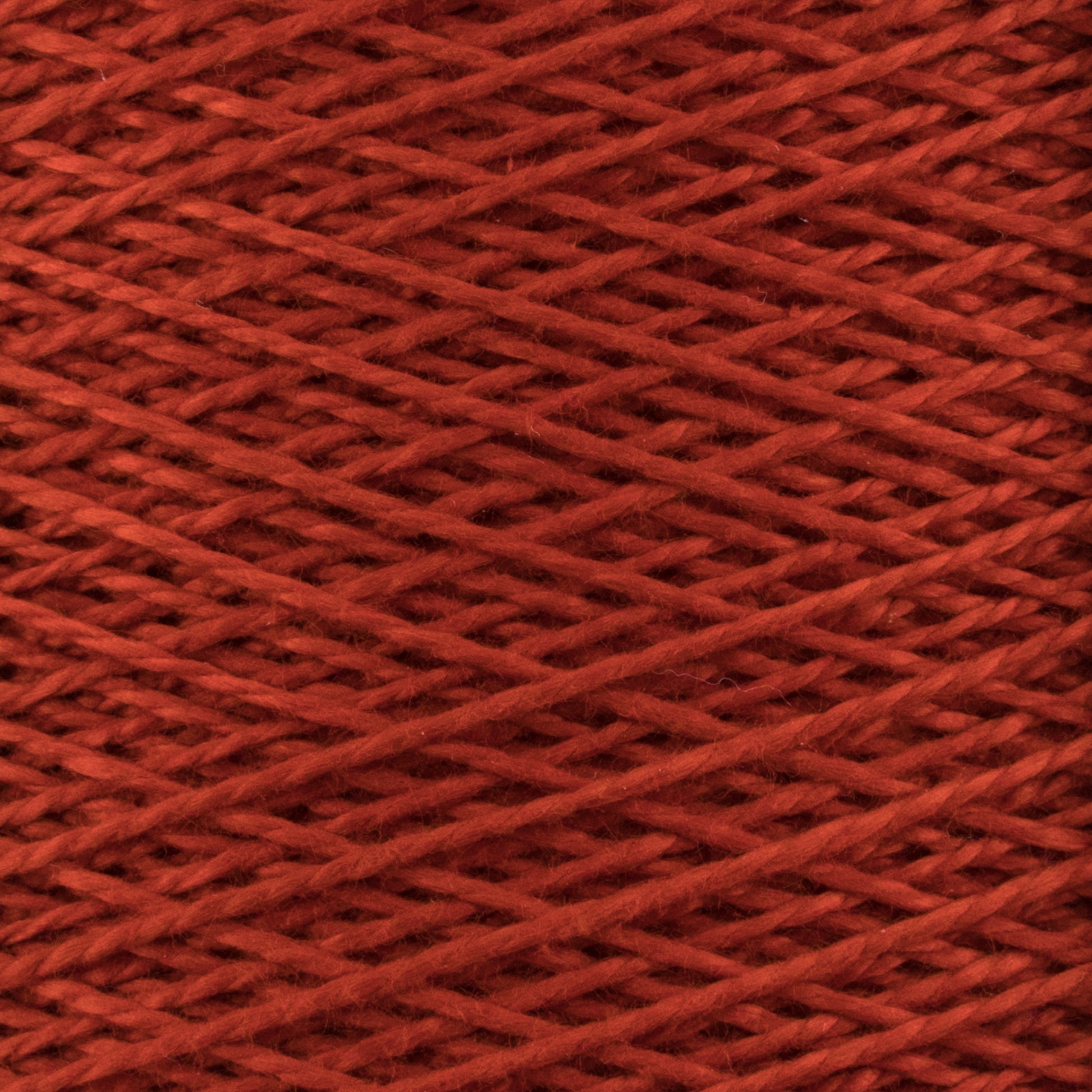 Close-up of a spool of Supreme Corp's 5/2 Pearl Cotton Yarn in red, showcasing the tightly packed crisscross pattern of the threads. The texture appears soft and slightly fuzzy, with a deep rich hue. The image highlights the intricate details and uniformity, making it perfect for delicate weaving projects.