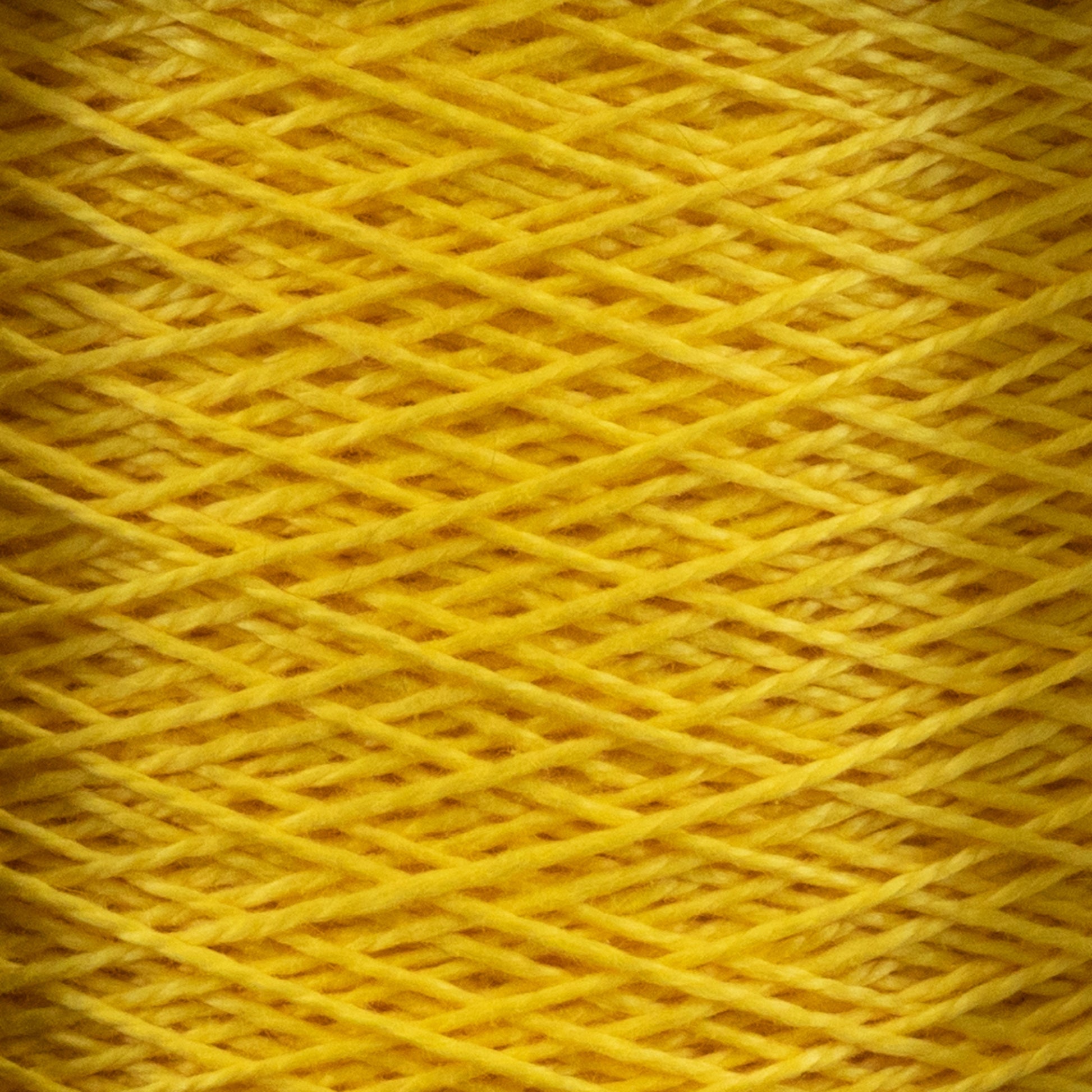 Close-up image of Supreme Corp's 5/2 Pearl Cotton Yarn | Mini-cone in yellow, wound in a crisscross pattern on a spool, showcasing the texture and intricate weave. The vibrant, mercerized cotton yarn is uniform throughout, making it perfect for weaving projects and creating a visually appealing, layered effect.