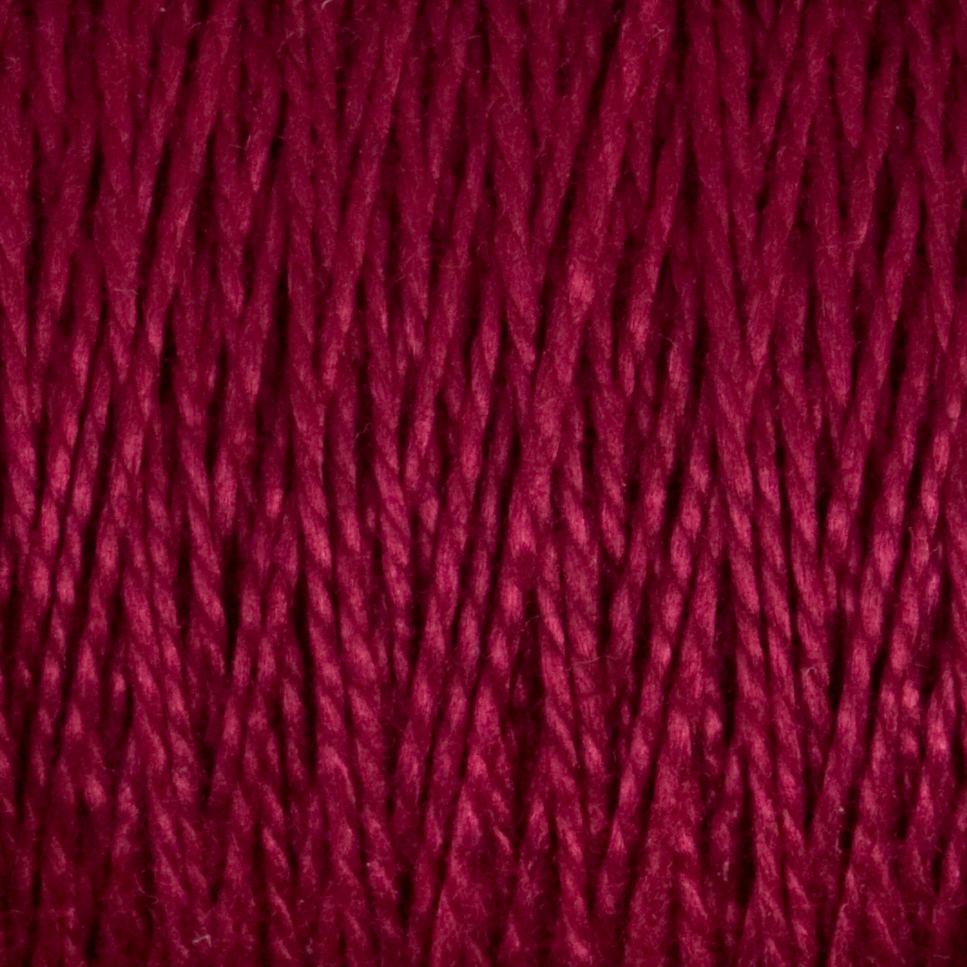 A close-up image of deep red 5/2 Pearl Cotton Yarn from Supreme Corp. The strands are tightly twisted and packed closely together, showcasing the texture and vibrant hue of this Mini-cone yarn. The tight twists and rich color give a sense of warmth and softness, perfect for weaving projects.