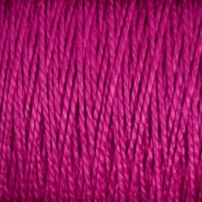 Close-up image of a tightly wound spool of 5/2 Pearl Cotton Yarn from Supreme Corp. The texture is clearly visible, showcasing the intertwined fibers and slight sheen of this versatile material. The vibrant magenta hue is prominent throughout the large cone.