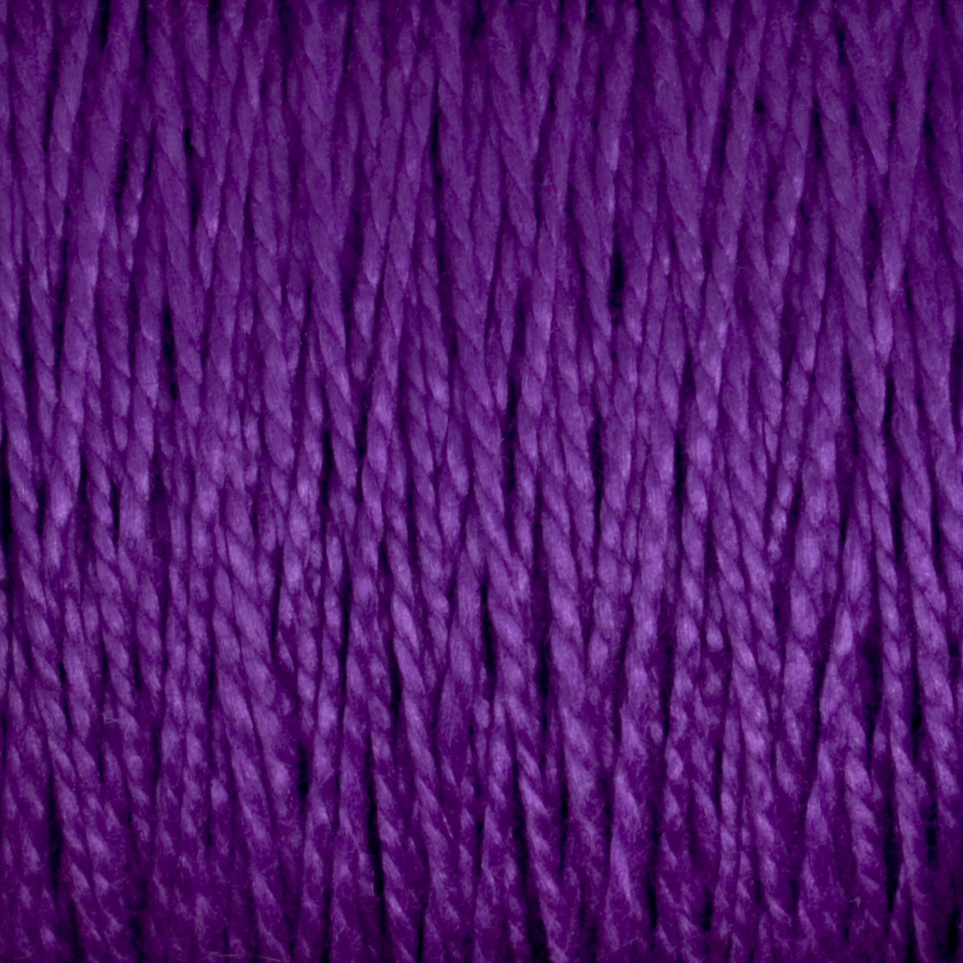 Close-up image of Supreme Corp's 5/2 Pearl Cotton Yarn | Mini-cone in purple, showcasing tightly wound, textured fibers running vertically across the frame. The mercerized cotton yarn appears soft and slightly shiny, with rich, vibrant coloration—perfect for intricate weaving projects.