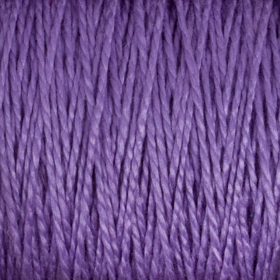 A close-up image of Supreme Corp's 5/2 Pearl Cotton Yarn | Large Cone in purple, showcasing detailed, tightly wound strands. The texture appears soft and smooth, with a consistent weave pattern throughout. The vibrant purple color gives a rich and uniform appearance to this versatile yarn.